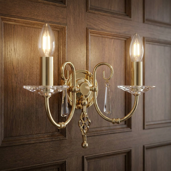 Aegean Polished Brass Double Wall Light with crystal accents, mounted on a dark wood-paneled wall.