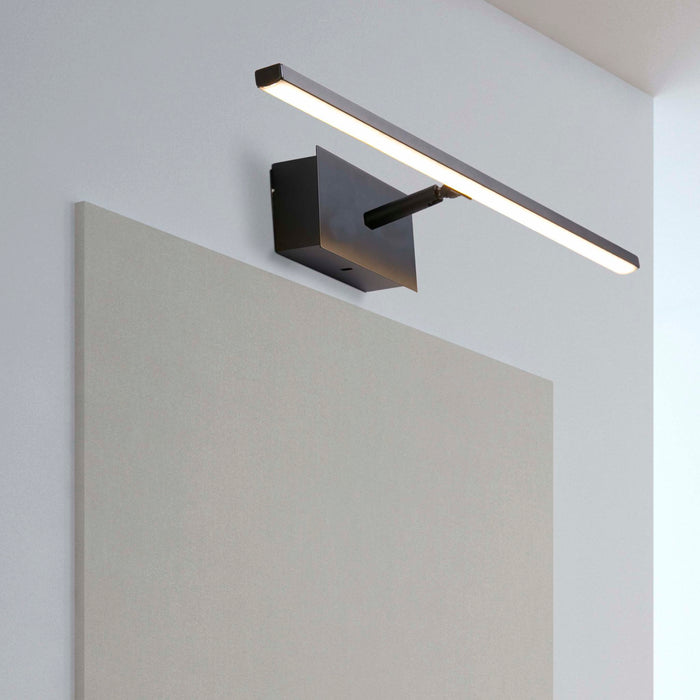 Amalfi black IP44 wall light lit above a plain canvas on a pale bathroom wall