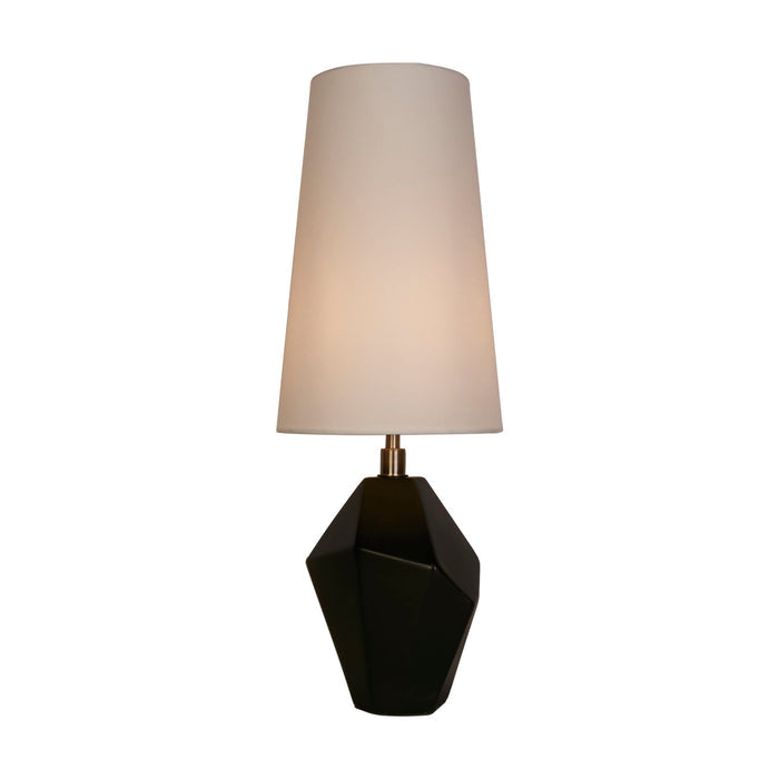 Apex table lamp lit with a tall white shade on a faceted black and antique brass base