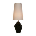 Apex table lamp lit with a tall white shade on a faceted black and antique brass base