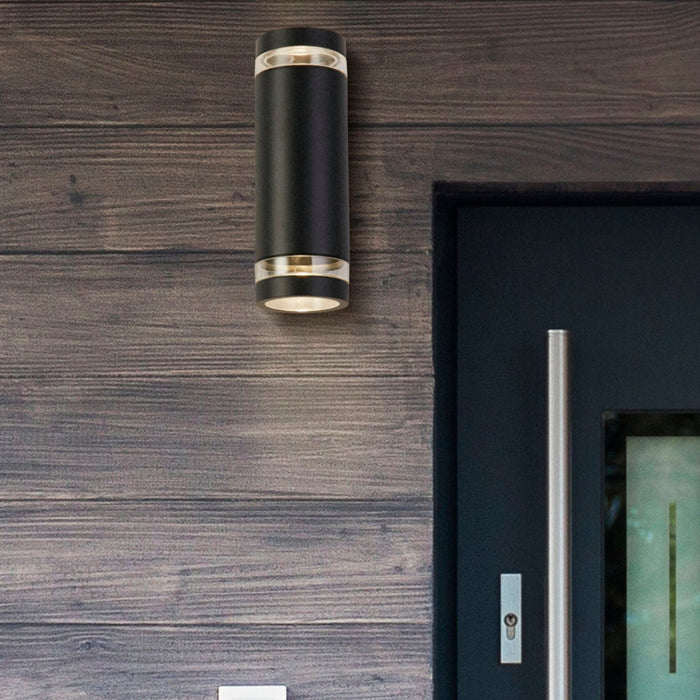 Austin black wall light glowing on dark timber cladding beside a modern front door