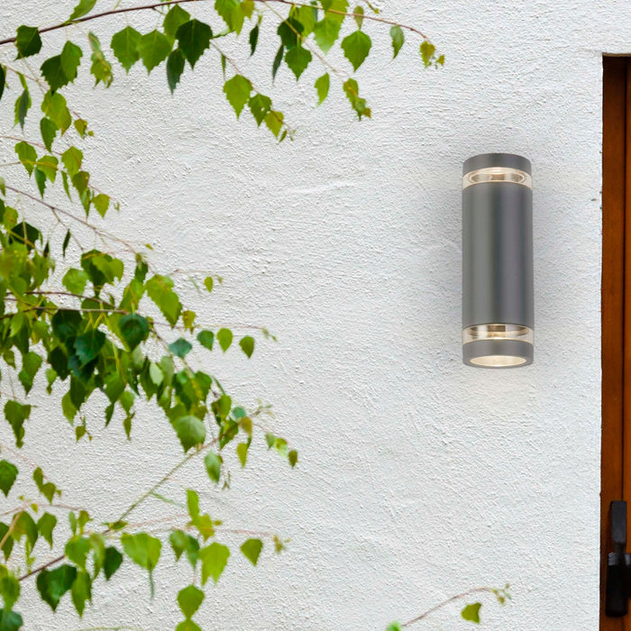 Austin grey up and down wall light on a white rendered house wall beside a door and birch foliage