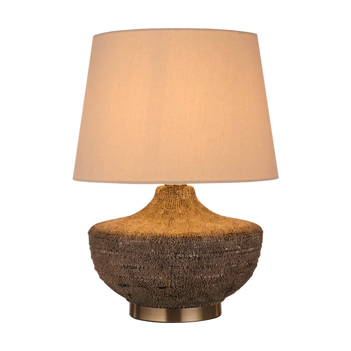 Avaya textured ceramic table lamp lit with a beige linen shade on a two-tone ribbed base