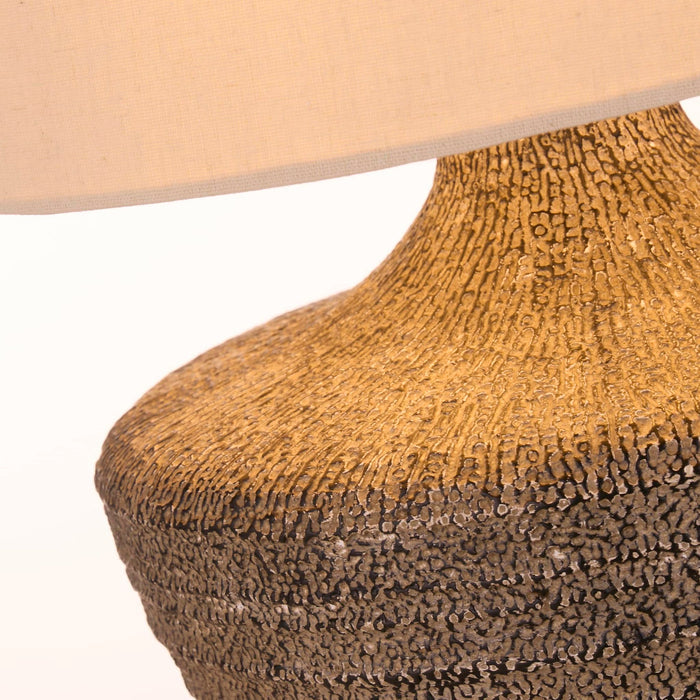 Close-up of the Avaya lamp's coarse ribbed ceramic base in ochre and charcoal tones