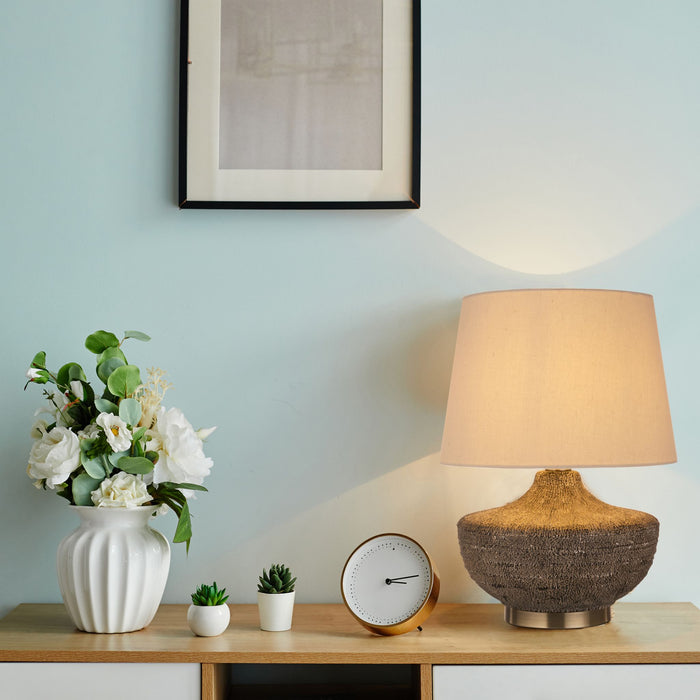 Avaya lamp lit on an oak console with white flowers a clock and small potted plants