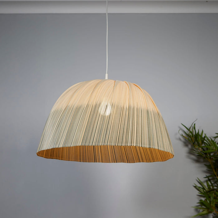 Bamboo ombre stripe dome pendant shade lit in a grey-walled room beside a leafy houseplant