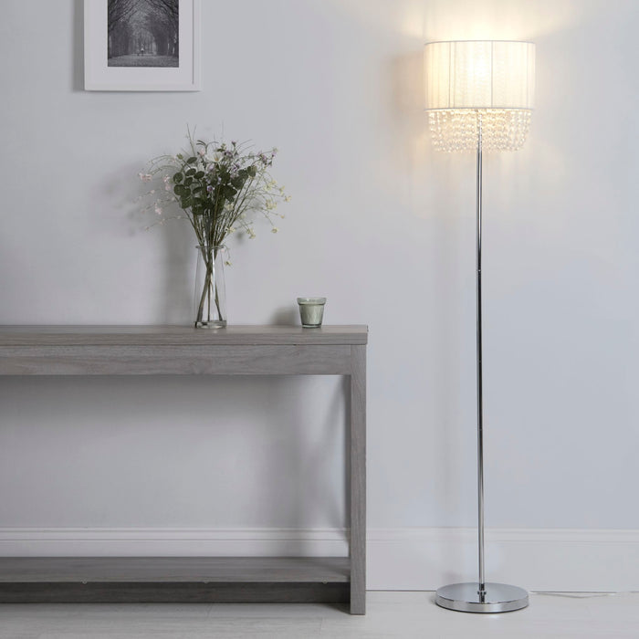 Bellano chrome beaded floor lamp glowing in a hallway by a console table with fresh flowers