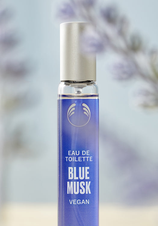 Blue Musk eau de toilette bottle with a blurred floral background