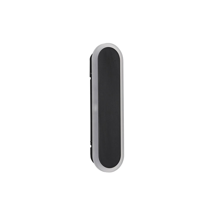 Bordo sand black oblong LED wall light mounted on a pale wall casting a warm glow