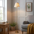 Burley brass floor lamp with a patterned ikat shade lighting up a cozy living room corner with a grey armchair.