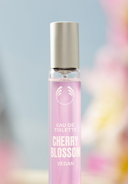 Pink perfume bottle labeled 'Cherry Blossom' with a blurred colorful background