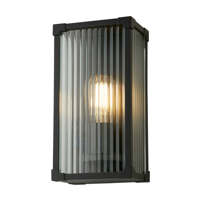 Cincinnati black outdoor wall light lit, box lantern with ribbed glass panels and warm filament bulb