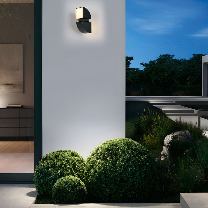 Dakota black LED wall light lit on a white villa wall above clipped box balls at twilight