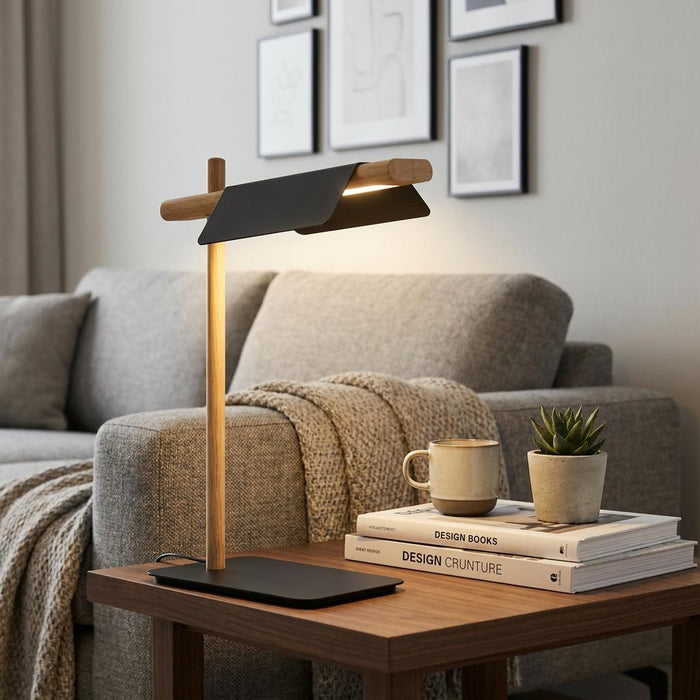 Modern black and wood LED table lamp on a side table next to books and a mug in a stylish living room.