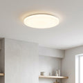 Round white LED flush ceiling light illuminating a minimalist kitchen with a soft, warm glow.