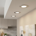 Three brushed nickel recessed ceiling lights casting warm white light in a contemporary home interior.