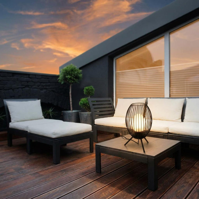 Eglo Fusignano black tripod outdoor table lamp on a modern patio table against a sunset sky.