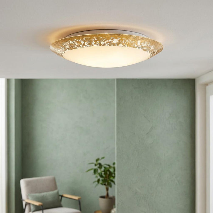 Round LED flush ceiling light with a gold leaf style rim illuminating a modern room with green walls.
