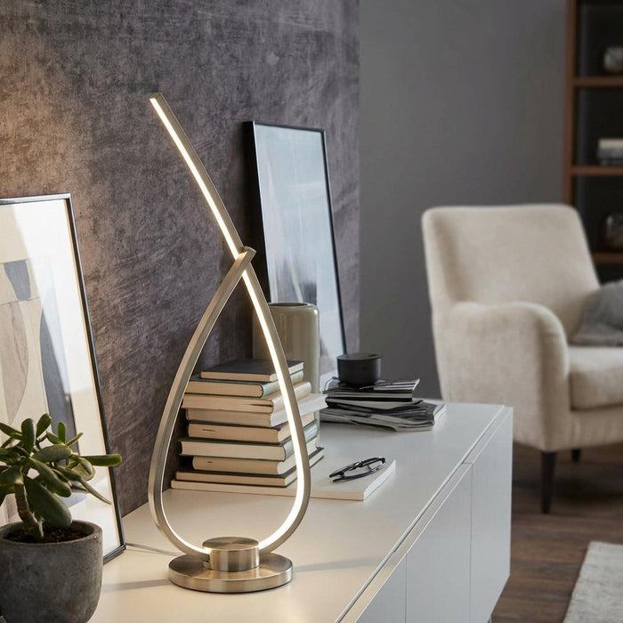 Nickel Eglo Palozza curved LED table lamp with a glowing loop design on a white sideboard.