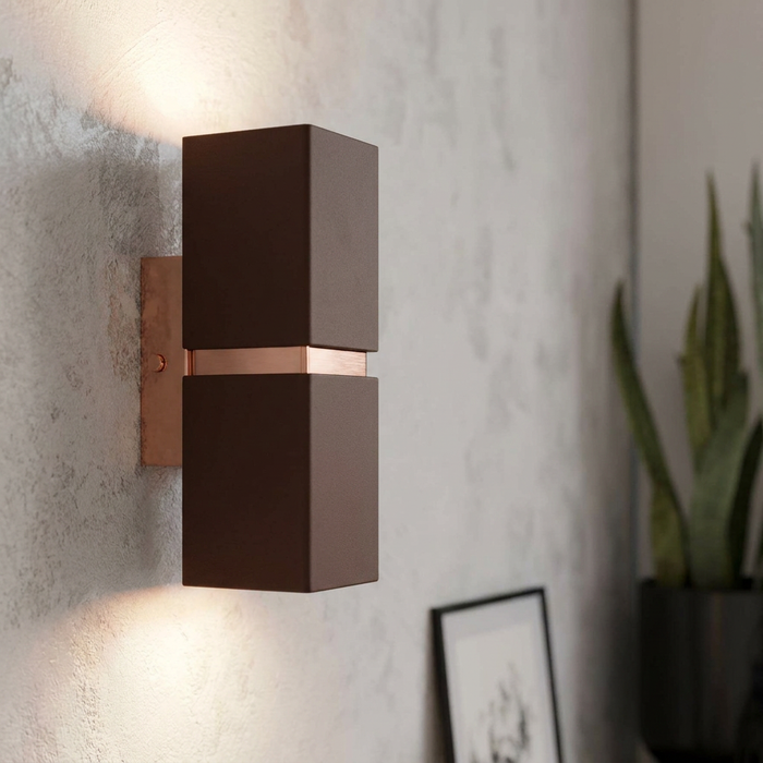 Brown and copper rectangular wall light illuminating a textured wall with upward and downward beams.