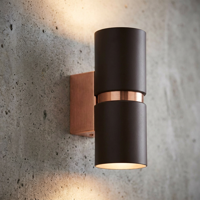 Eglo Passa brown and copper up-and-down wall light mounted on a textured concrete wall, emitting warm light.
