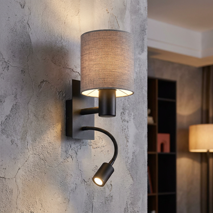 Black wall lamp with a grey fabric drum shade and flexible reading light mounted on a textured wall.