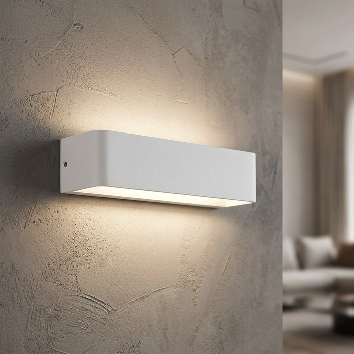 White rectangular LED wall light casting a warm up-and-down glow on a textured grey wall.