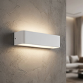 White rectangular LED wall light casting a warm up-and-down glow on a textured grey wall.