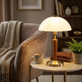 Eglo Solo 1 table lamp with a bronze base, wood stem, and white domed shade on a marble table in a cozy living room.