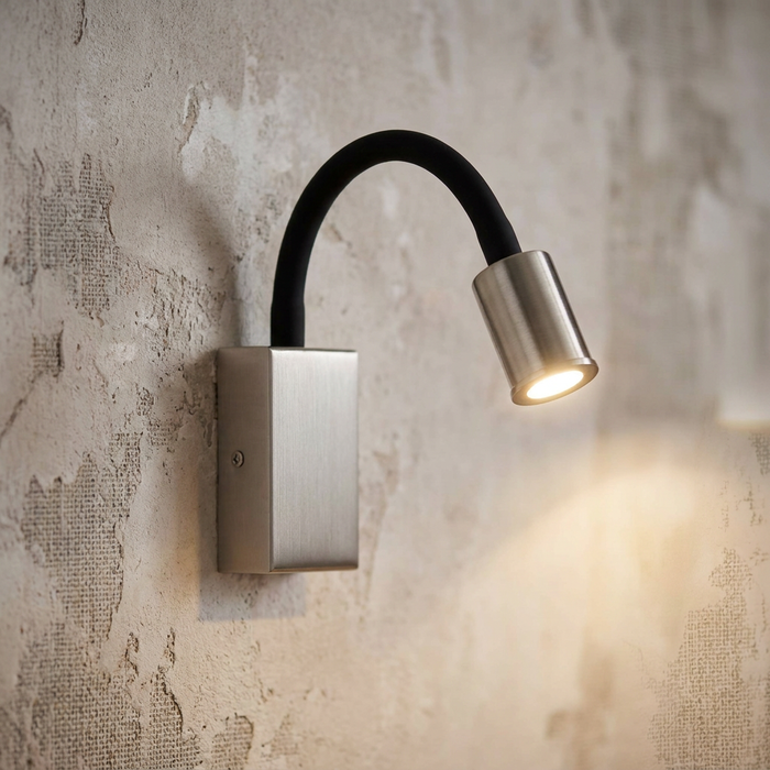 Brushed nickel LED wall light with a flexible black neck mounted on a textured wall, casting a warm light.