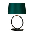 Elegant matt black table lamp lit with an emerald velvet shade on a ring base