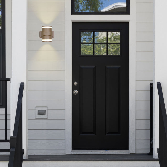 Grip gold wall light lit beside a black front door on white clapboard cladding
