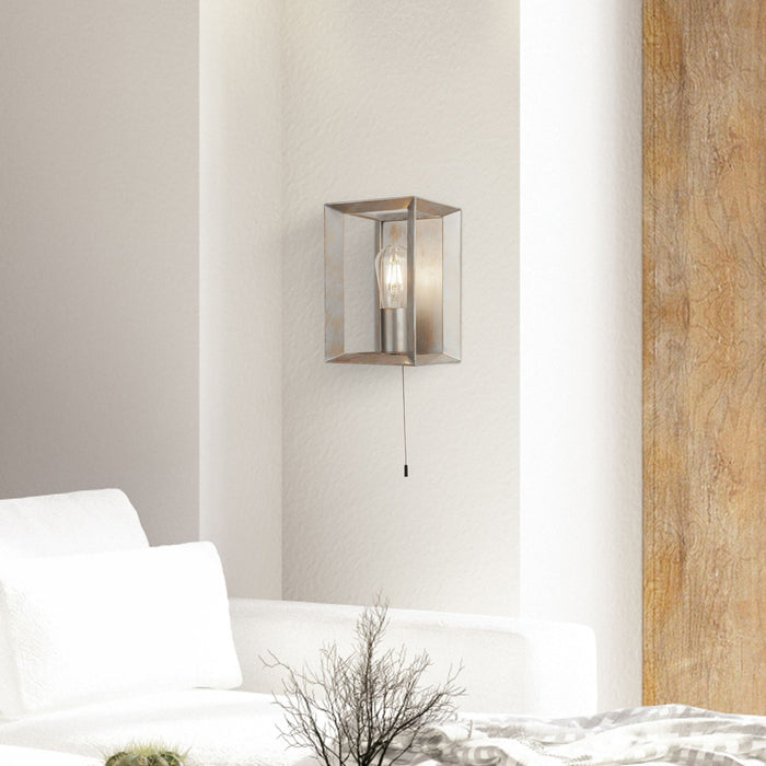 Bedroom wall with the Heaton box wall light and pull cord beside a white chair and plant