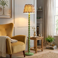 Green bobbin-style floor lamp with a zigzag ikat shade next to a yellow armchair in a bright living room.