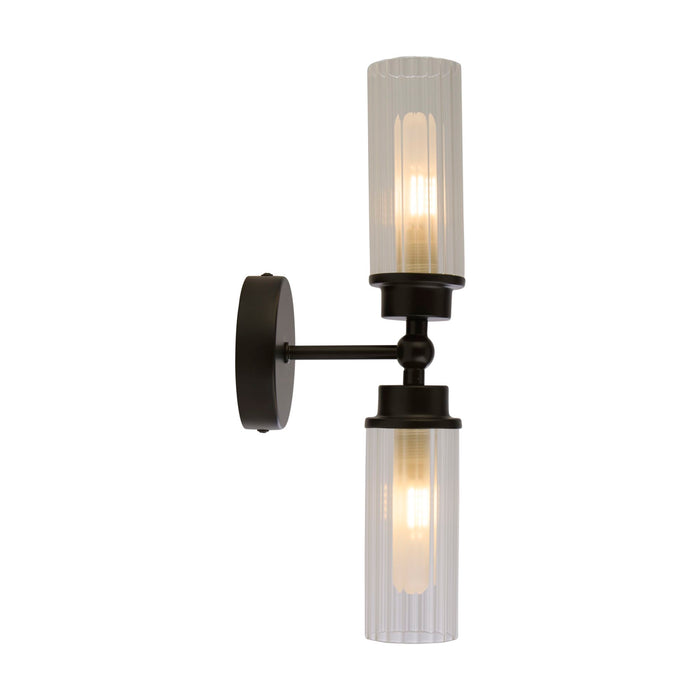 Imperial matt black bathroom wall light lit, two ribbed clear glass cylinders on a black stem