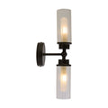 Imperial matt black bathroom wall light lit, two ribbed clear glass cylinders on a black stem