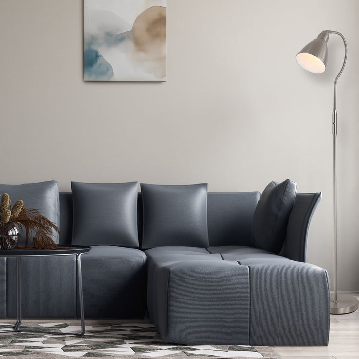 Satin nickel curved floor lamp lit beside a grey corner sofa, patterned rug and abstract artwork