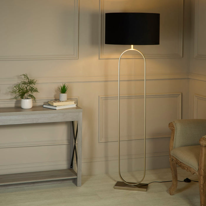 Modish bronze floor lamp with black shade lit beside a console table and carved chair