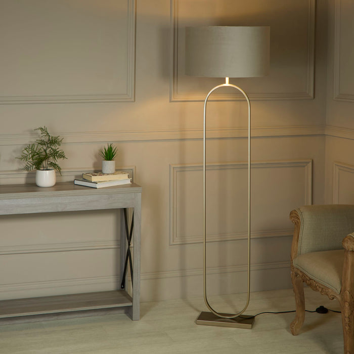 Modish floor lamp with taupe shade glowing in a panelled hallway by a console table and armchair