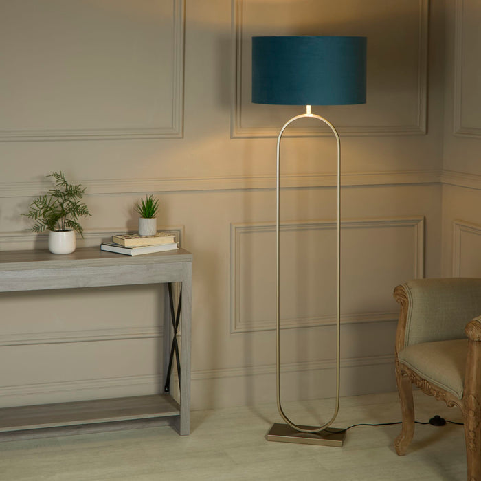 Modish bronze floor lamp with teal shade lit beside a grey console table, plants and carved chair