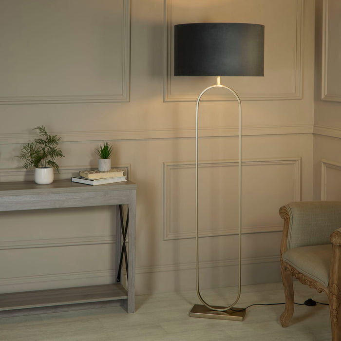 Modish floor lamp with dark grey shade lit in a panelled hallway beside a console and chair