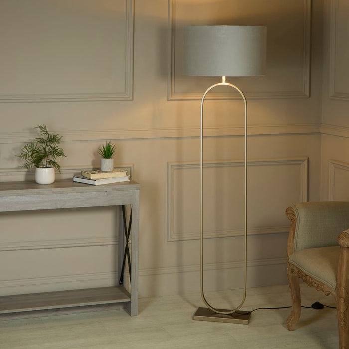 Modish bronze floor lamp with grey shade lit in a panelled hall by a console and armchair