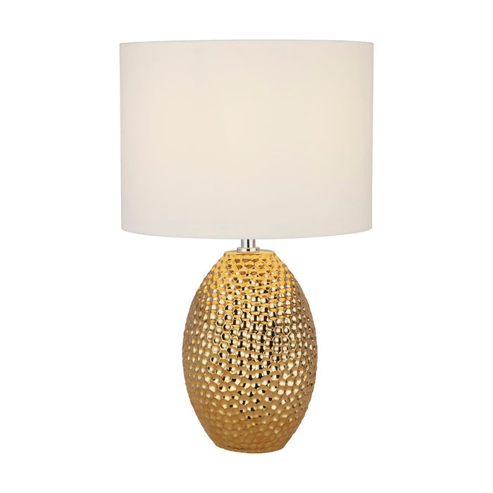 Nadine gold table lamp lit with a dimpled gold ceramic base and white drum shade