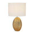 Nadine gold table lamp lit with a dimpled gold ceramic base and white drum shade