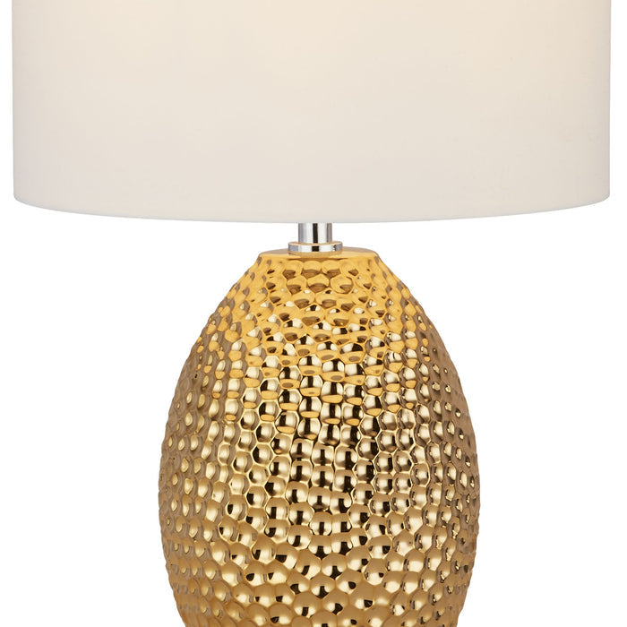 Close-up of the Nadine lamp glossy gold dimpled ceramic base beneath its white shade