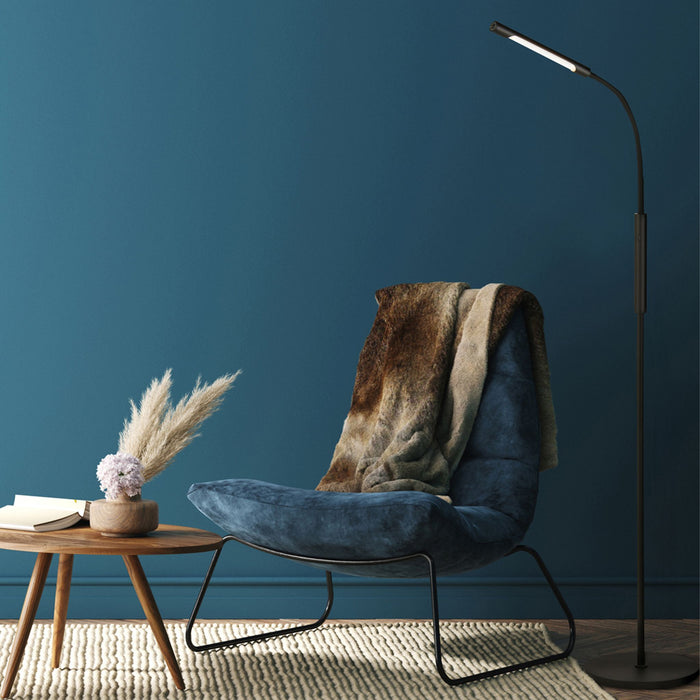 Plume black floor lamp beside a blue armchair with fur throw against a deep blue wall