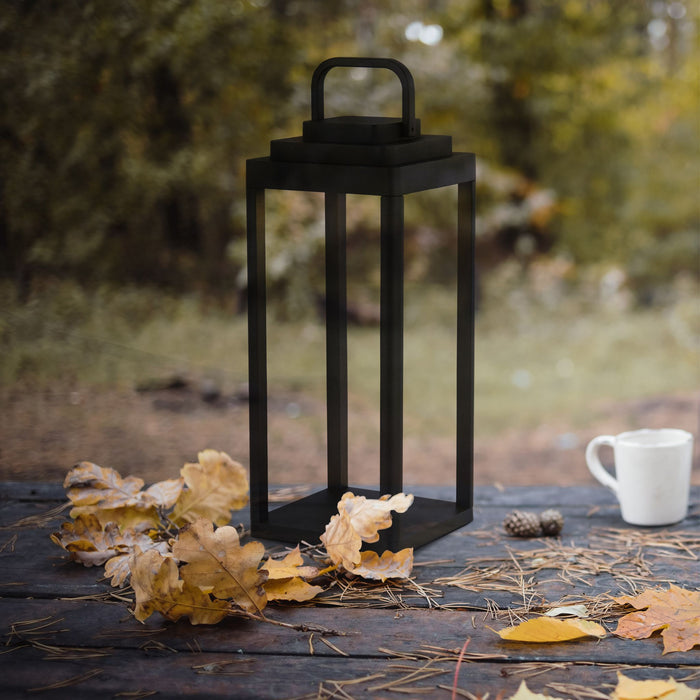 Portobello black lantern on a rustic garden table with autumn oak leaves and a white mug
