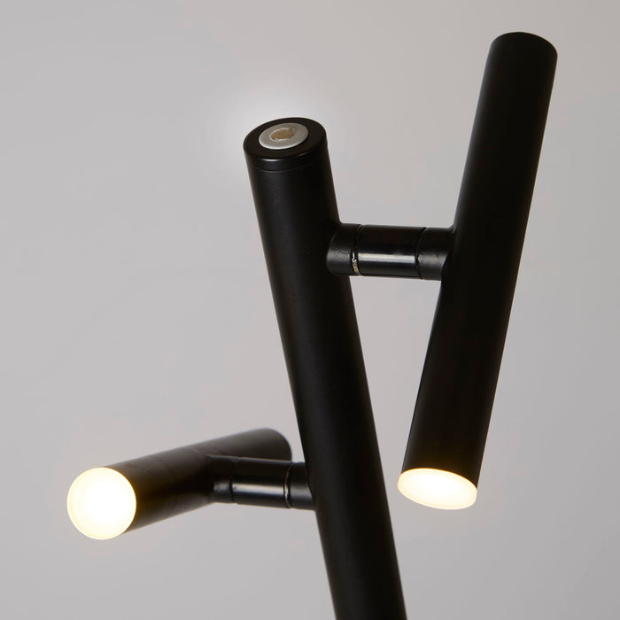Close-up of the black LED floor lamp's twin cylinder heads and adjustable knuckle joints lit warm