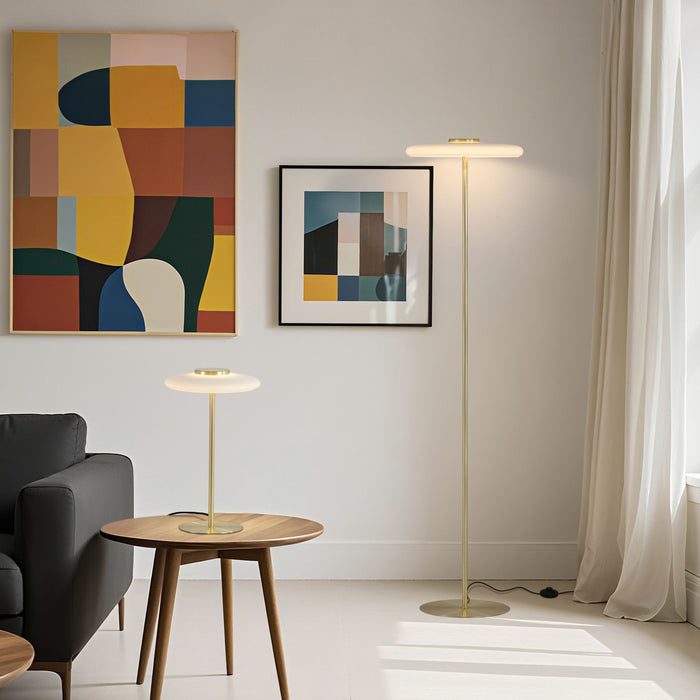 Record brass floor lamp lit in a living room with bold abstract art and a matching table lamp