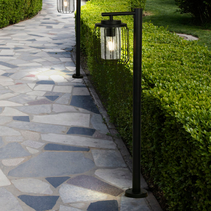 Reed black post lights lining a stone garden path beside a clipped green hedge